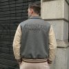 Front lifestyle model view of the custom men's heritage varsity jacket displaying the open-button layout, shirt-style fold collar, tan leather chest band, and matching striped ribbed waist.