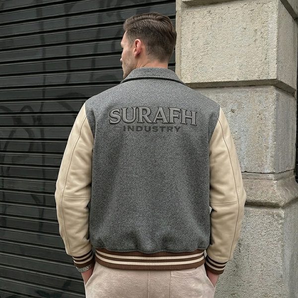 Front lifestyle model view of the custom men's heritage varsity jacket displaying the open-button layout, shirt-style fold collar, tan leather chest band, and matching striped ribbed waist.