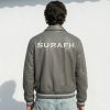 Back perspective of a private label gray leather varsity jacket showcasing premium flat embroidery across the upper yoke panel for bulk branding inspiration.