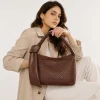 Woman wearing brown crocodile-embossed leather shoulder bag with knot handle, side view