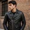 Man wearing gothic spider web biker jacket, back view on urban brick wall